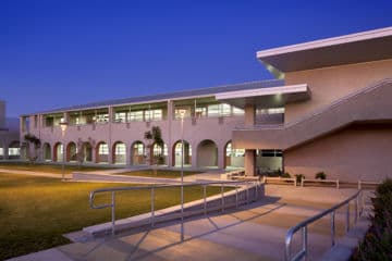 A completed campus building lit warmly at dusk